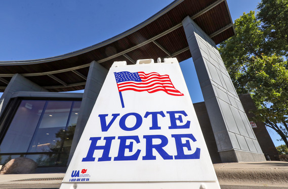Image of a sign that reads "Vote Here" in front of Plymouth City Hall