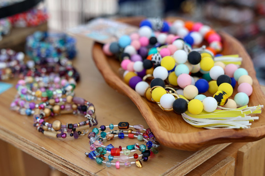 Photo of colorful beaded bracelets on a wooden display shelf.