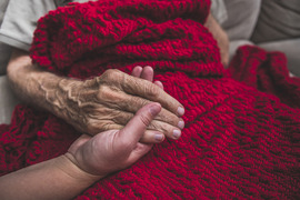 Family members holding hands over red blanket