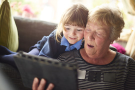 Grandmother and granddaughter laughing and looking at tablet together