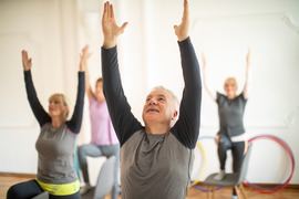 Man and group of people doing chair yoga together in a studio