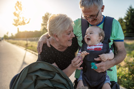 Grandparents outside with baby, grandpa holding baby in baby carrier