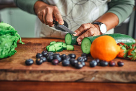 Hands cutting cucumber on cutting board