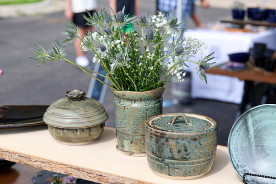 image of a pottery vase and two containers with lids. In the vase is a bouquet of wild flowers.