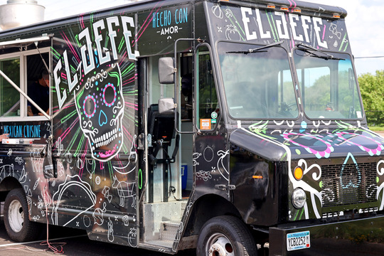 Image of a black food truck with colorful designs in pinks, greens, blues and whites and the text "El Jefe"
