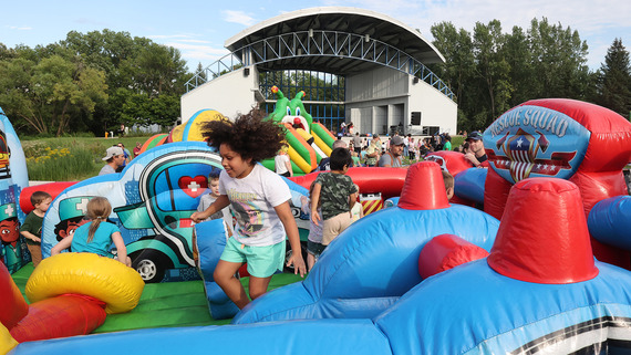 Photo of colorful inflatable bouncy equipment with a child jumping in the middle.