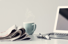 Current events image- newspaper with cup of coffee and reading glasses on table