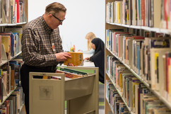 Man restocking shelf at Ramsey County Library