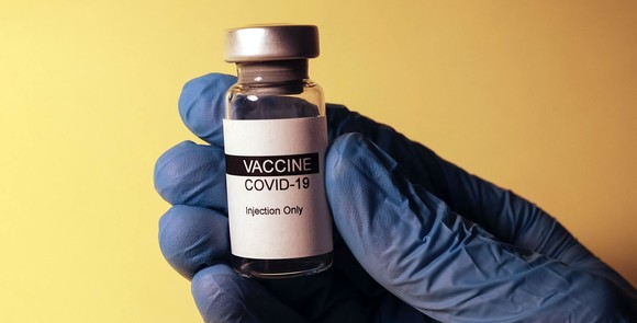 Stock photo: gloved hand holding a vial of COVID-19 vaccine