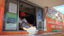 Woman prepares takeout order in the West Indies Soul Food truck.