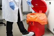 Laboratory worker placing waste in biohazard container