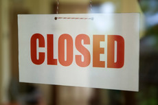 Sign hanging in window of storefront with word "Closed"