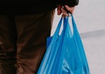 Person carrying a blue plastic bag