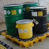 Several properly closed hazardous waste containers on a plastic pallet 