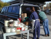 Man and woman transferring hazardous waste out of vehicle onto rolling cart