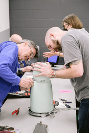 People fixing a tea kettle