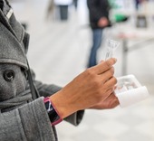 Closup of the hands of someone holding a COVID-19 saliva test