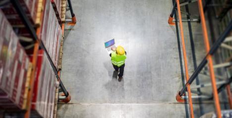 Bird's eye view of warehouse and employee with laptop