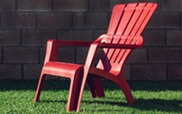 Red plastic lawn chair on a grassy lawn