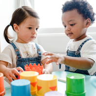 Two toddlers plays with blocks