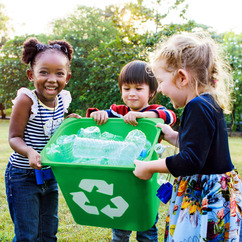 Three kids hold a green recycle bin