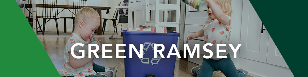 Two small kids putting recyclables in a recycling bin