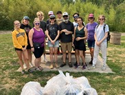 Group of volunteers standing in park next to trash backs after a clean-up volunteer event