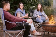 Three people sitting by a campfire