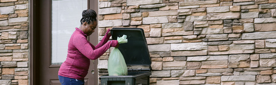 Woman putting a food scrap bag into her trash cart