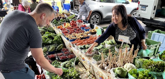 Wana Vue Kiatoukaysy Family Farm pointing to produce for customer at Richfield Farmers Market 9-14-2024