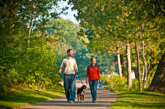 Two people walking a dog after picking up pet waste