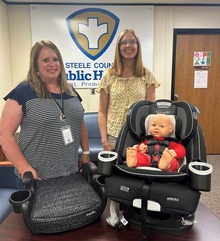 two car seat technicians with a baby doll in a car seat