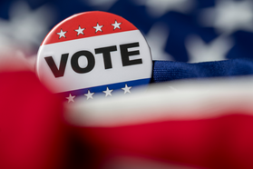 Vote pin with blurred american flag background