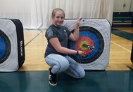 Sydney King poses next to an archery target.