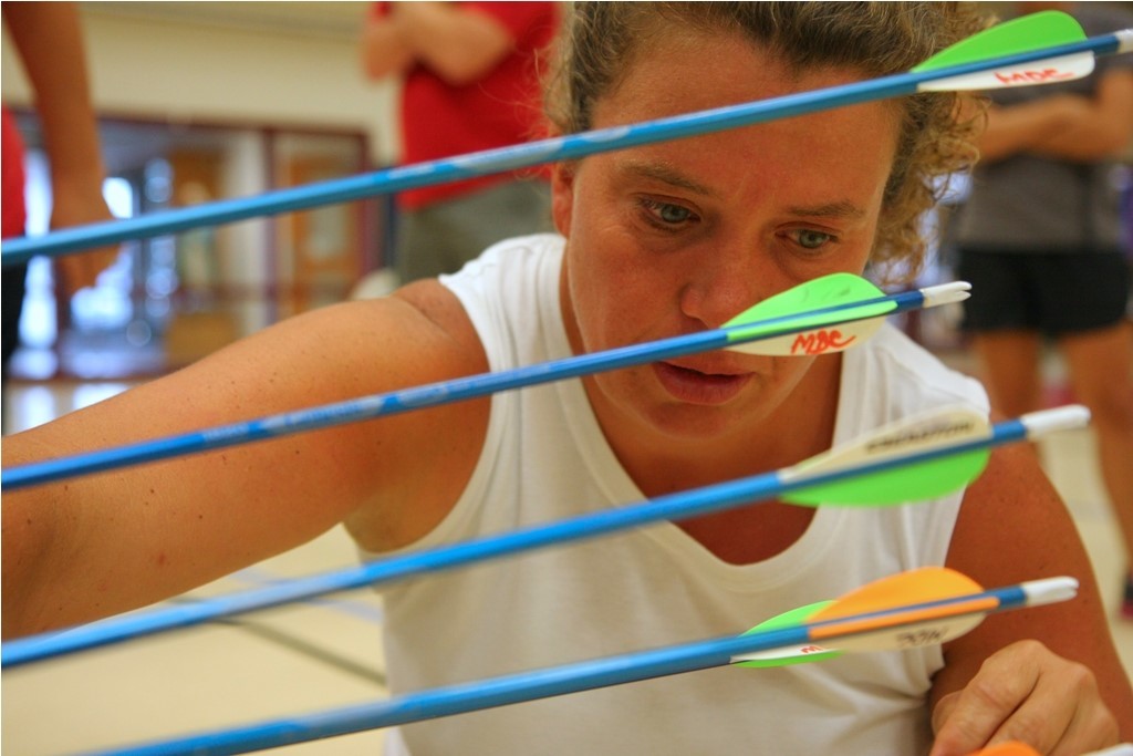 A teacher looks at a group of arrows in an archery target.