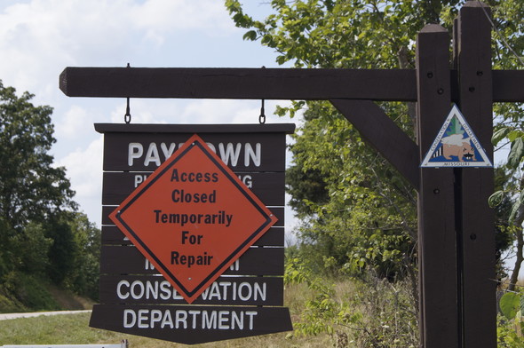 An orange closure sign covers the brown Paydown Access area sign on the side of US Hwy 63. 