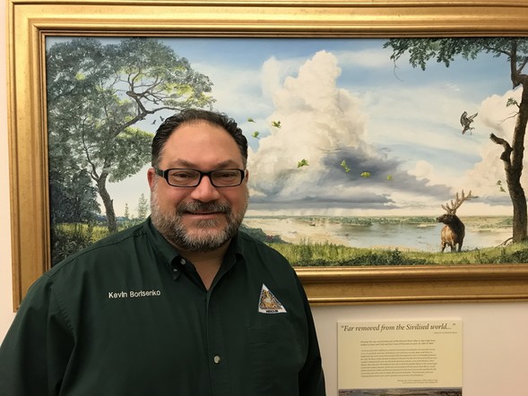 Kevin Borisenko stands in front of a framed landscape painting at MDC’s Central Office in Jefferson City. 