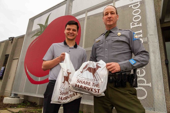 Jack Baran of OFS and MDC Conservation Agent Capt. Scott Corley hold bags of donated venison in front of the OFC building.