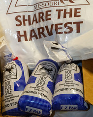 A closeup of bags of frozen venison in front of a Share the Harvest logo bag. (8x10 crop)