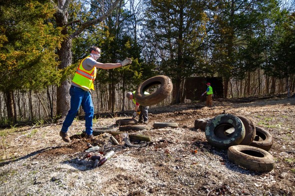 An MDC staff member throws tires collected on the area into a pile.