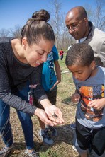 A woman shows a young boy a baby turtle in the palm of her hand.