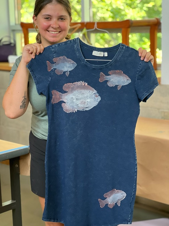Blonde woman standing with denim dress with fish prints