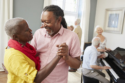 man dancing with older woman in long term care facility