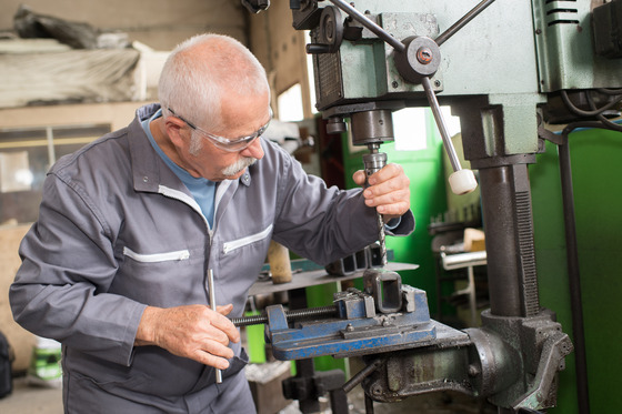 An older worker adjusts a piece of machinery