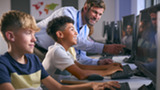 Students Looking at a computer with their teacher 