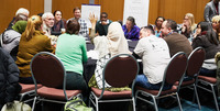 Woman raising hand during roundtable discussion at 2018 Community Connections Conference