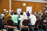 Woman raising hand during roundtable discussion at 2018 Community Connections Conference