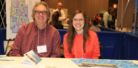 Two commissioners at NCEC table at Community Connections Conference 2018