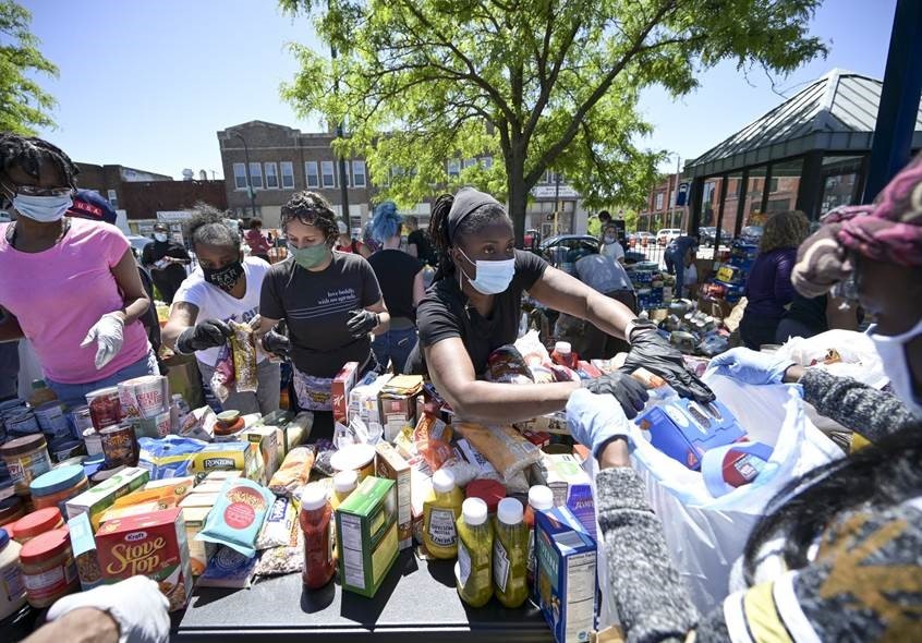 Woman in mask distributing items at food shelf