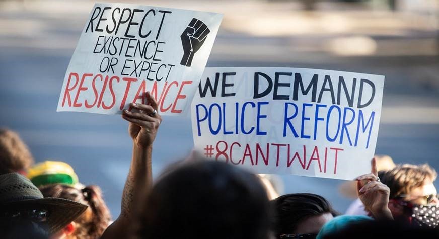 Protest signs reading We Demand Police Reform